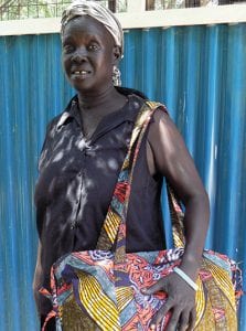 Sudanese woman proudly holds a bag sewn in brightly coloured fabric.